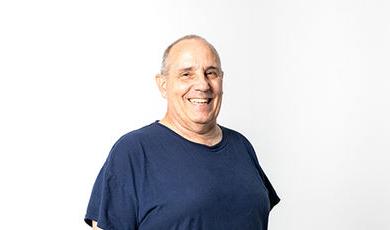 Ronald Pace smiles while standing in front of a white background